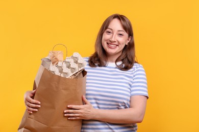 Photo of Recycling. Smiling woman with bag full of different waste paper on yellow background