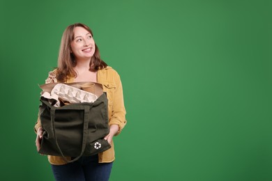 Photo of Recycling. Smiling woman with bag full of different waste paper on green background. Space for text