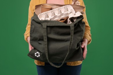 Photo of Recycling. Woman with bag full of different waste paper on green background, closeup
