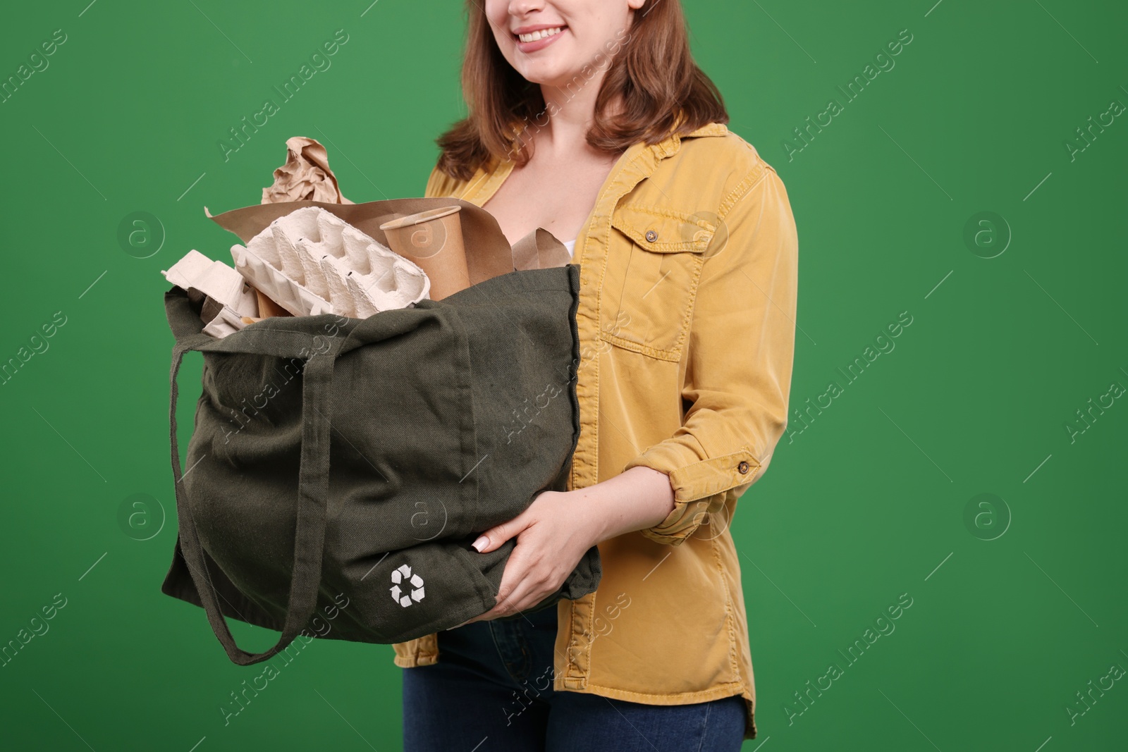 Photo of Recycling. Woman with bag full of different waste paper on green background, closeup