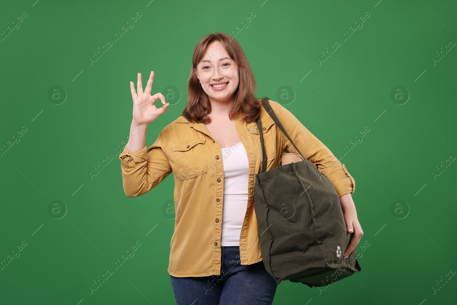 Photo of Recycling. Woman with bag full of different waste paper showing OK gesture on green background