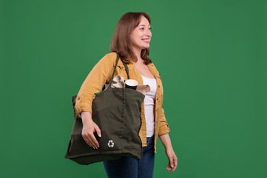 Photo of Recycling. Smiling woman with bag full of different waste paper on green background