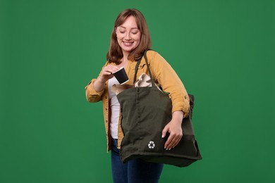 Photo of Recycling. Smiling woman with bag full of different waste paper on green background