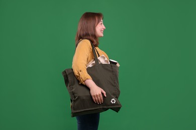 Photo of Recycling. Smiling woman with bag full of different waste paper on green background