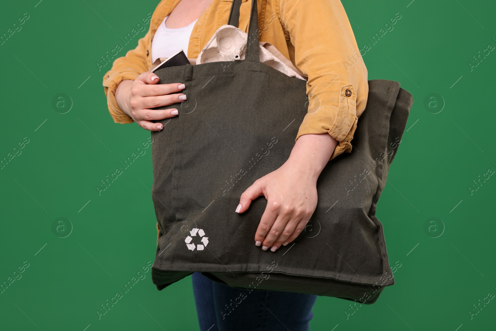 Photo of Recycling. Woman with bag full of different waste paper on green background, closeup