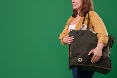 Photo of Recycling. Woman with bag full of different waste paper on green background, closeup. Space for text