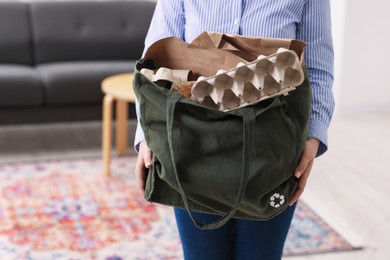 Photo of Recycling. Woman with bag full of different waste paper indoors, closeup