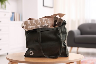 Photo of Recycling. Bag full of different waste paper on wooden table indoors