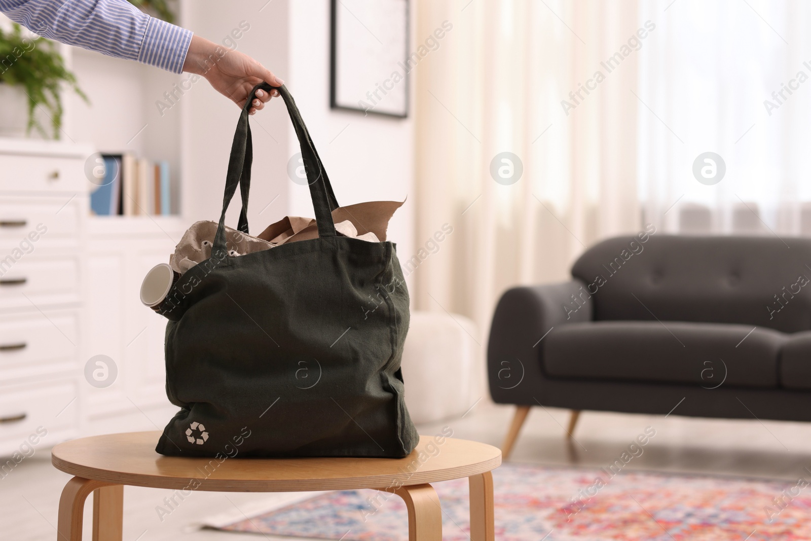 Photo of Recycling. Woman with bag full of different waste paper indoors, closeup
