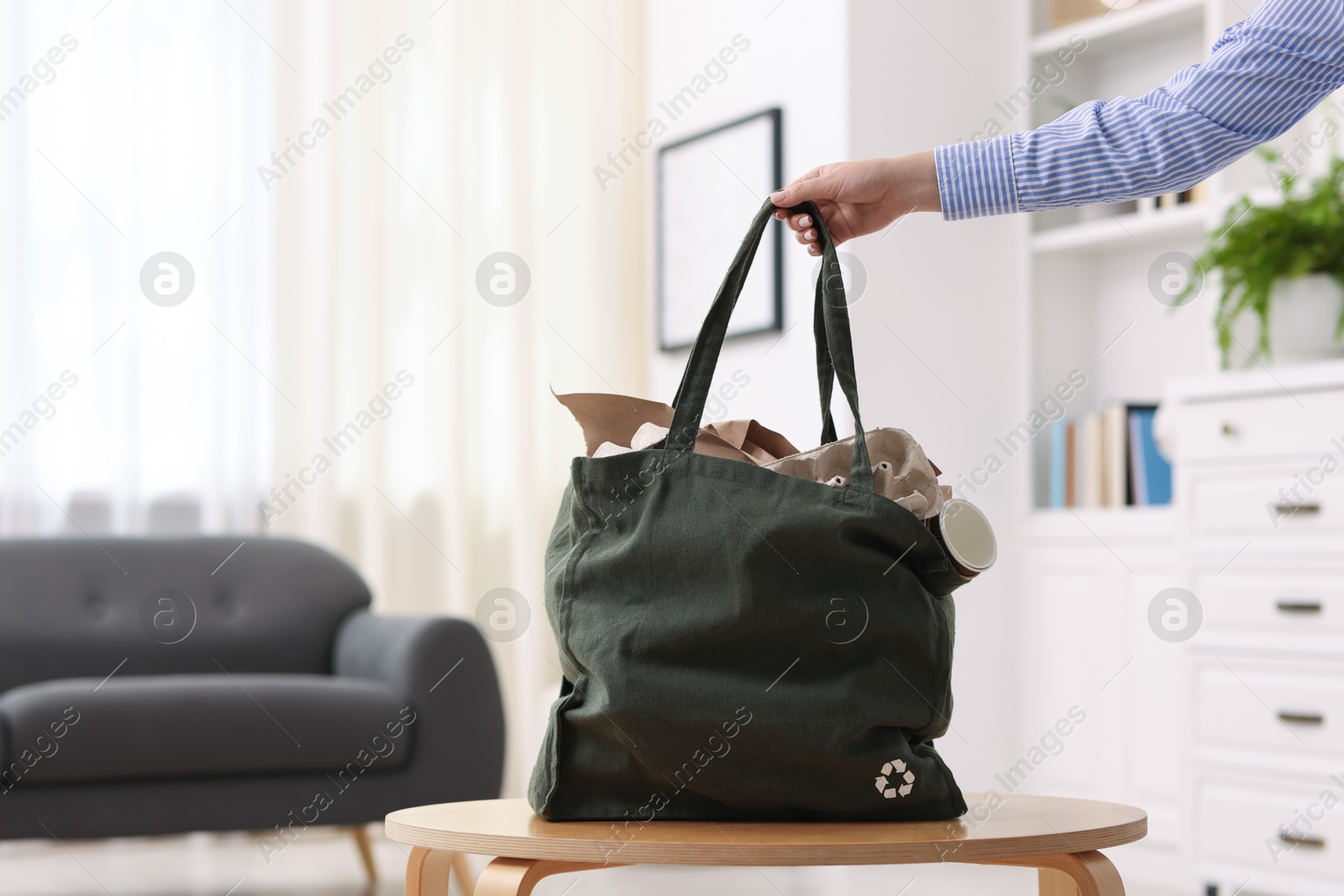Photo of Recycling. Woman with bag full of different waste paper indoors, closeup