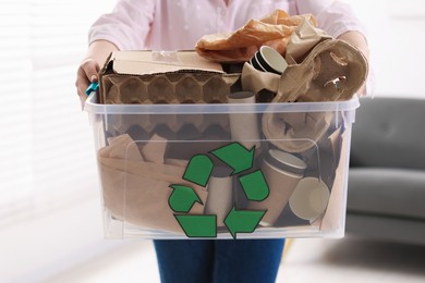 Photo of Recycling. Woman holding plastic box with different waste paper indoors, closeup