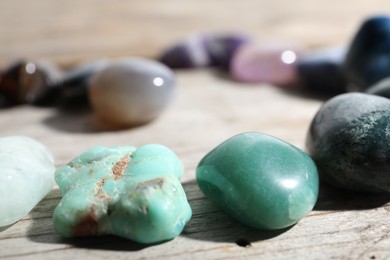 Photo of Many different healing stones on wooden table, closeup