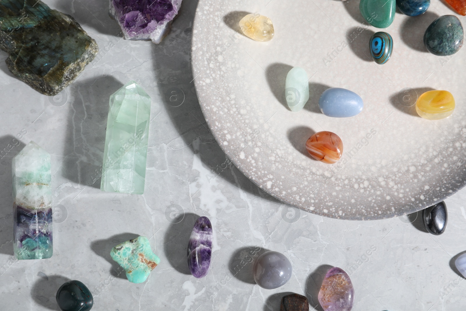 Photo of Many different healing stones on light grey table, flat lay