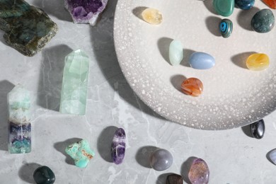 Photo of Many different healing stones on light grey table, flat lay