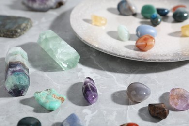 Photo of Many different healing stones on light grey table, closeup