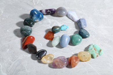 Photo of Many different healing stones on light grey table, closeup