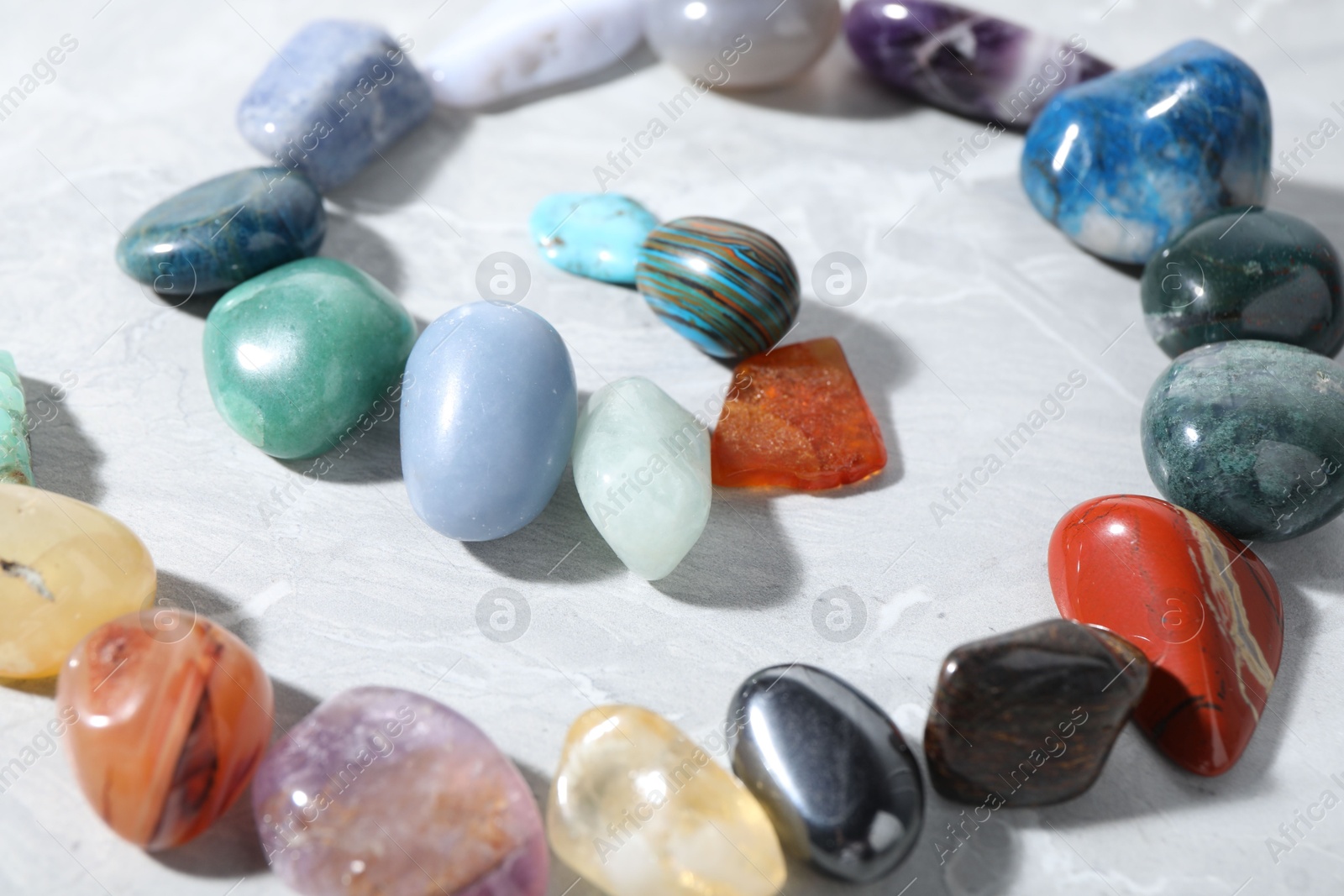 Photo of Many different healing stones on light grey table, closeup