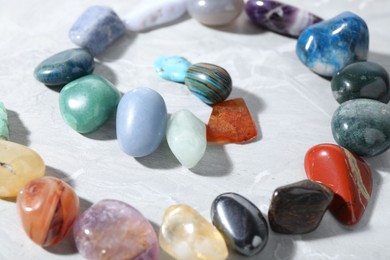 Photo of Many different healing stones on light grey table, closeup