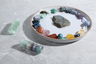 Photo of Many different healing stones on light grey table, closeup
