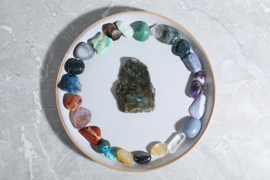 Photo of Many different healing stones on light grey table, top view