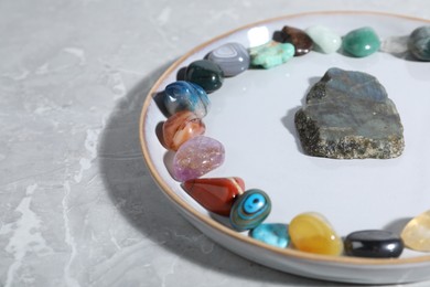 Photo of Many different healing stones on light grey table, closeup. Space for text