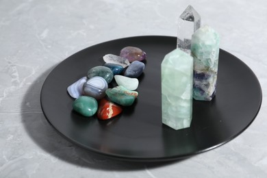 Photo of Many different healing stones on light grey table, closeup