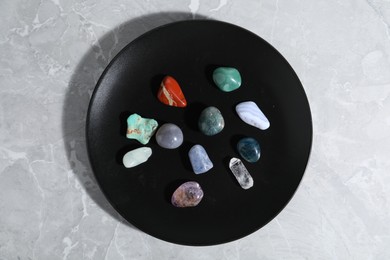 Photo of Many different healing stones on light grey table, top view