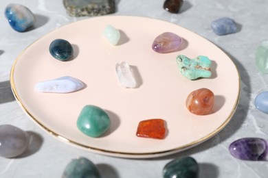 Photo of Many different healing stones on light grey table, closeup
