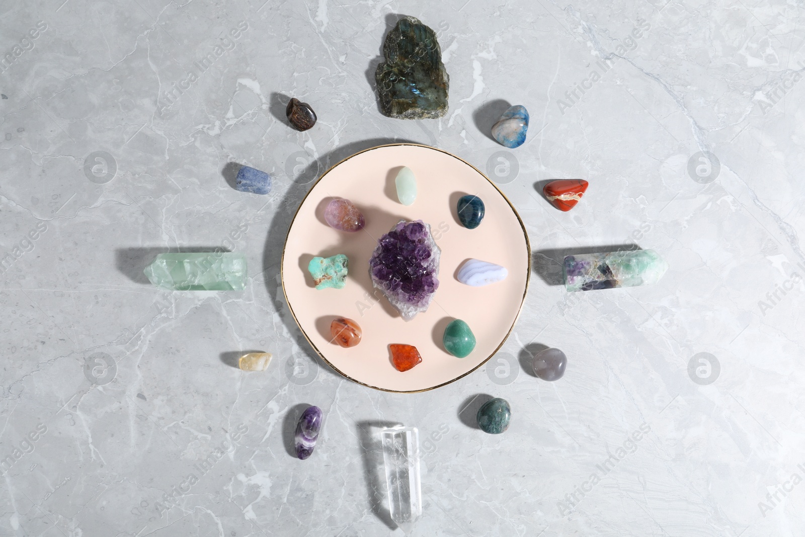 Photo of Many different healing stones on light grey table, flat lay