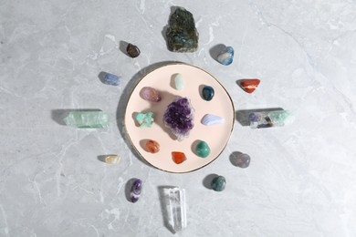 Photo of Many different healing stones on light grey table, flat lay