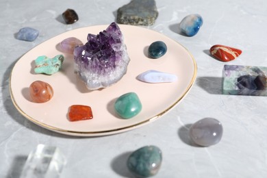 Photo of Many different healing stones on light grey table, closeup