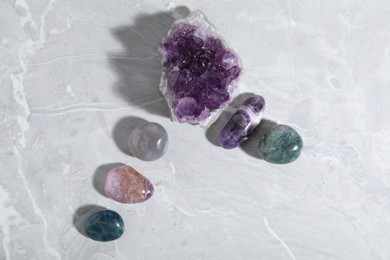 Photo of Many different healing stones on light grey table, flat lay