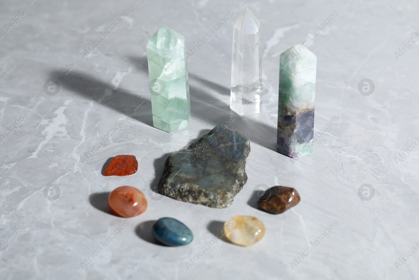 Photo of Many different healing stones on light grey table, closeup