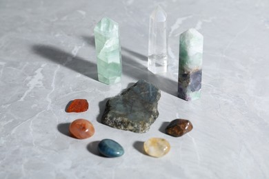 Photo of Many different healing stones on light grey table, closeup