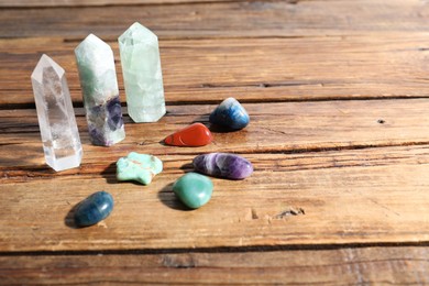 Photo of Different healing stones on wooden table, closeup. Space for text