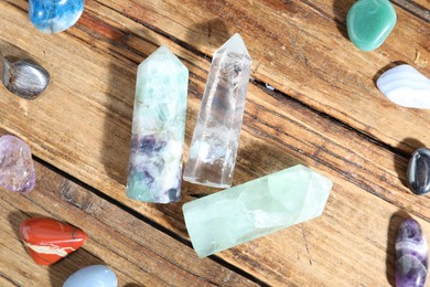 Photo of Different healing stones on wooden table, flat lay