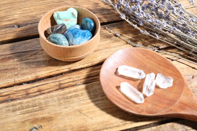 Photo of Different healing stones and lavender on wooden table, closeup