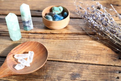 Photo of Different healing stones and lavender on wooden table, closeup