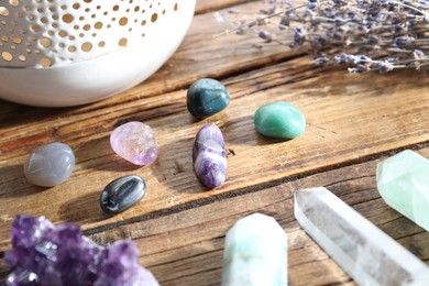 Photo of Different healing stones and lavender on wooden table, closeup