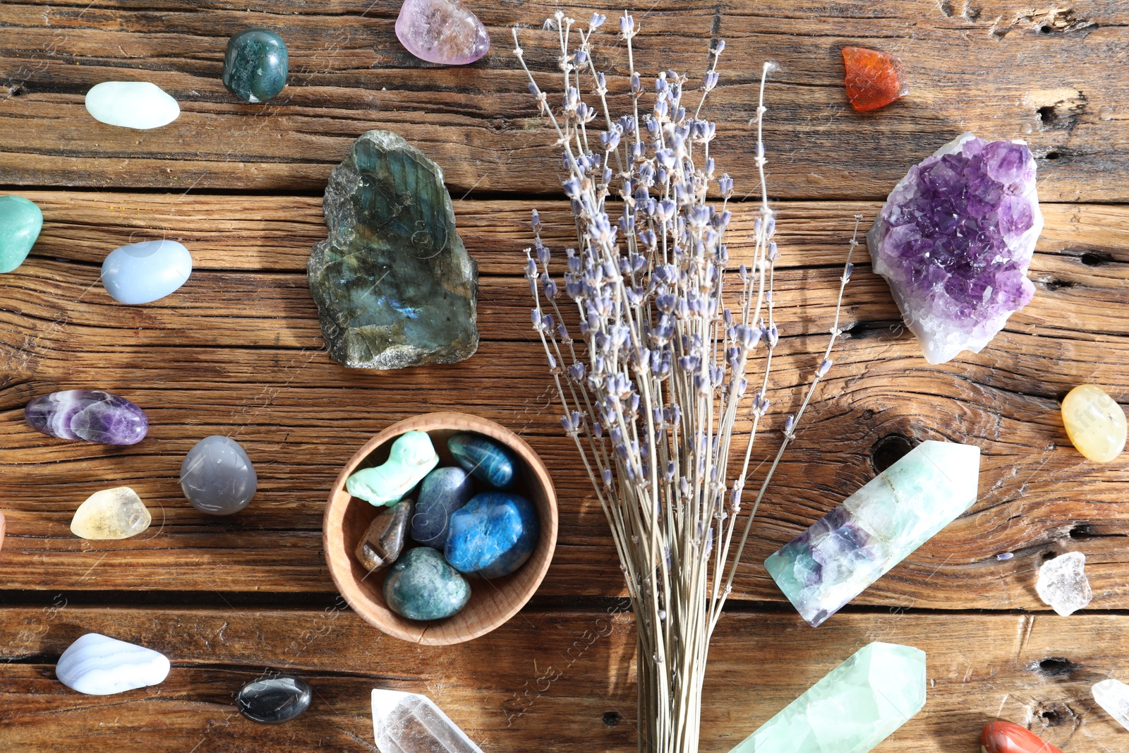 Photo of Different healing stones and lavender on wooden table, flat lay