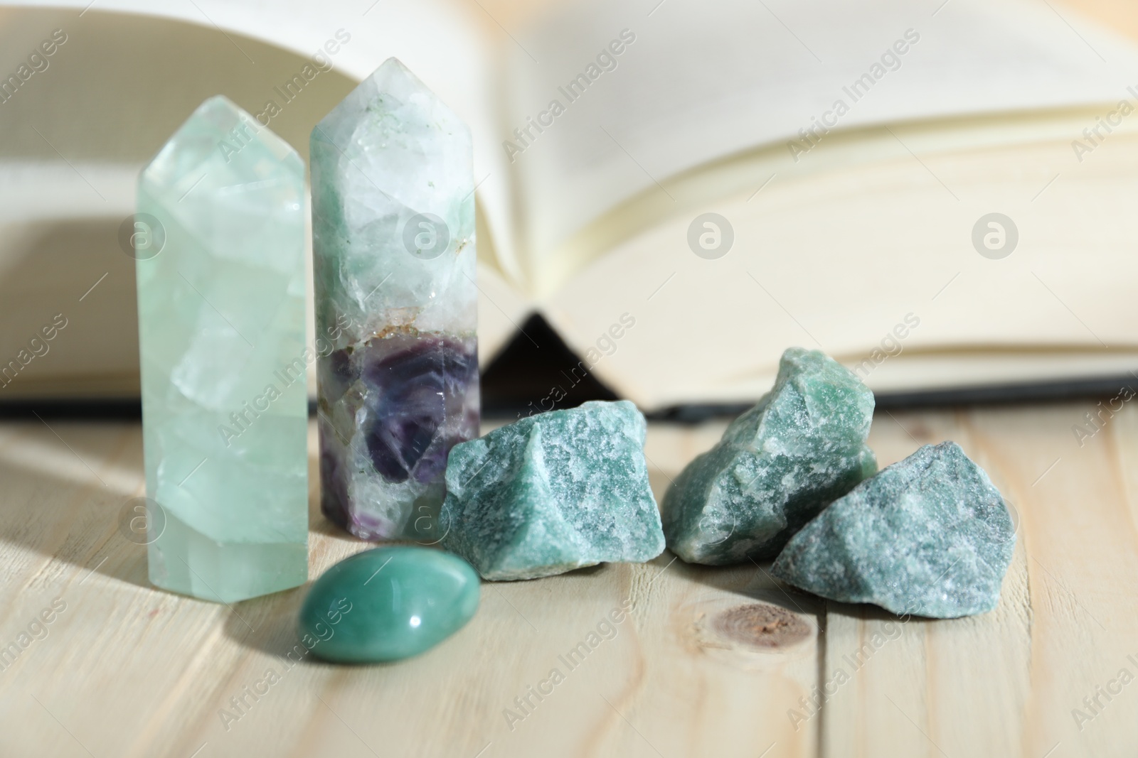 Different healing stones and book on wooden table, closeup Photo of Different healing stones and book on wooden table, closeup