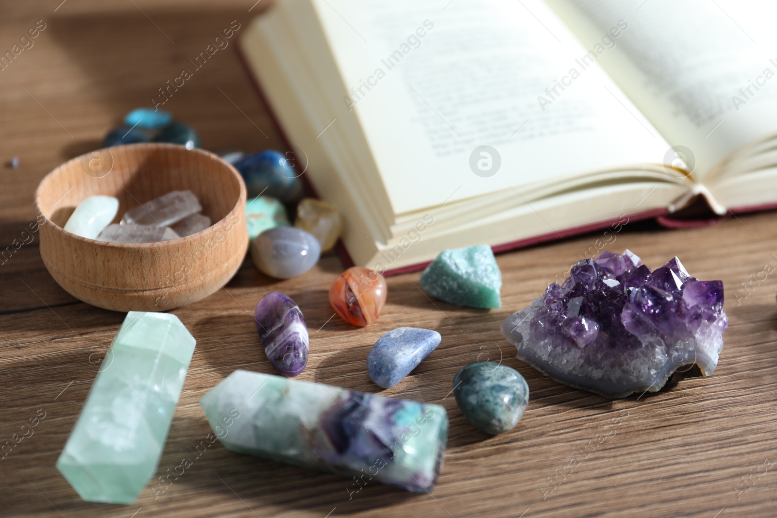 Different healing stones and book on wooden table, closeup Photo of Different healing stones and book on wooden table, closeup