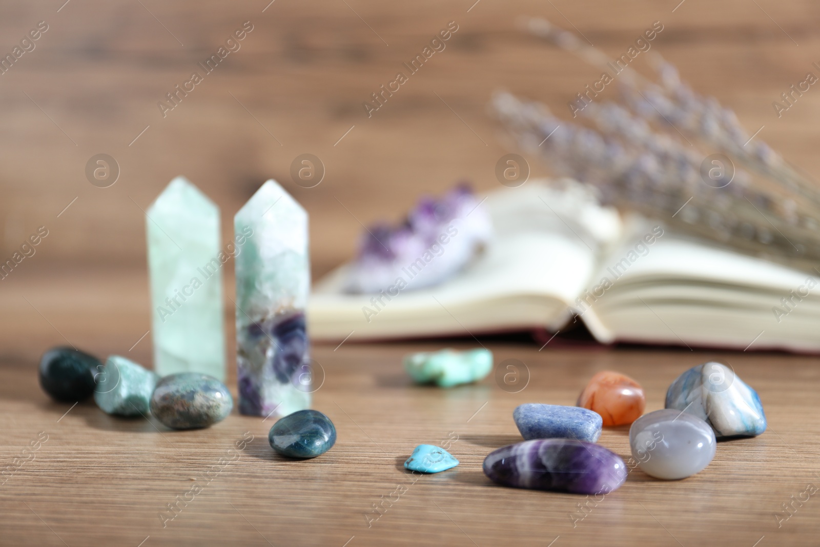Different healing stones and book on wooden table, closeup Photo of Different healing stones and book on wooden table, closeup