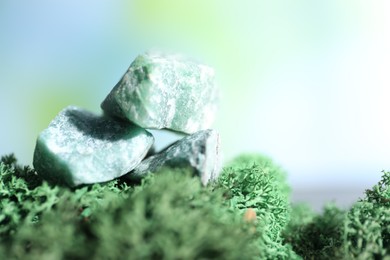 Photo of Healing stones on green moss against blurred background, closeup. Space for text