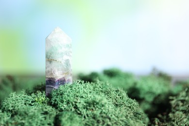 Photo of Healing stone on green moss against blurred background, closeup. Space for text