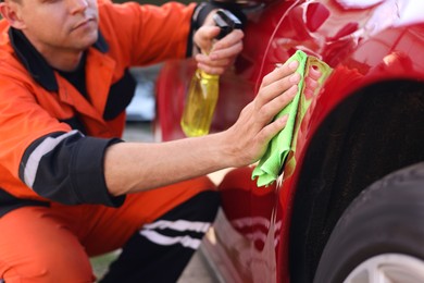 Photo of Man wiping car with green microfiber rag outdoors, closeup