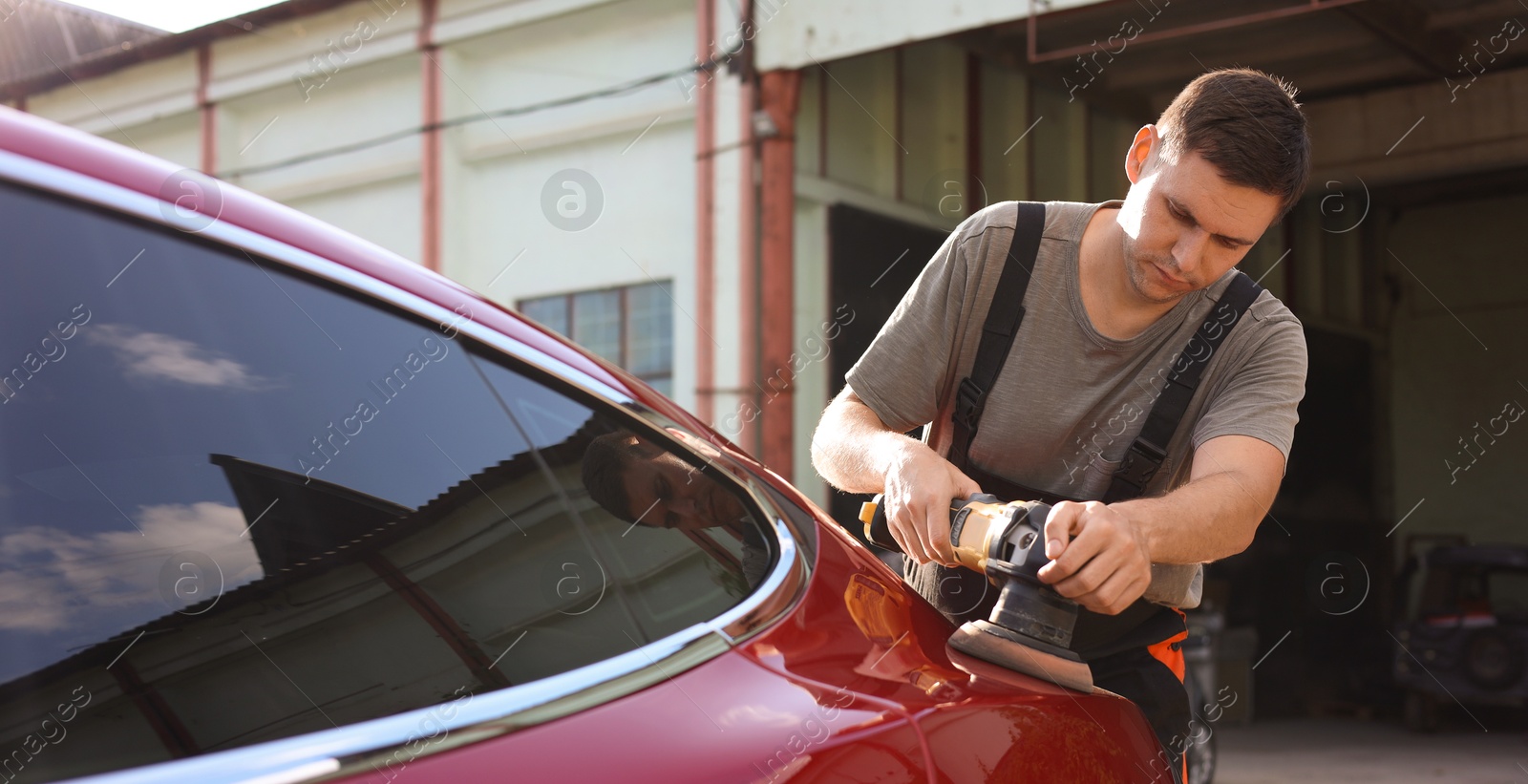 Man polishing car with orbital polisher outdoors Photo of Man polishing car with orbital polisher outdoors