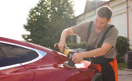 Photo of Man polishing car with orbital polisher outdoors
