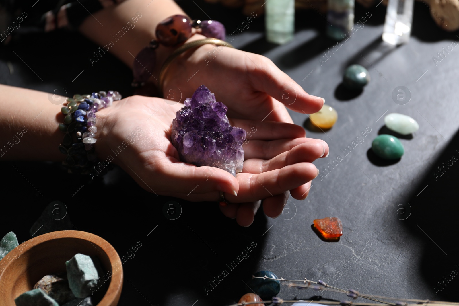 Photo of Woman with healing stones at black table, closeup