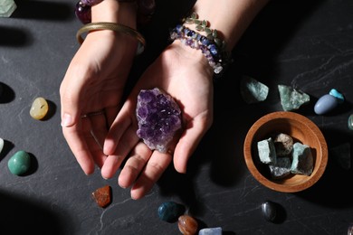 Photo of Woman with healing stones at black table, closeup
